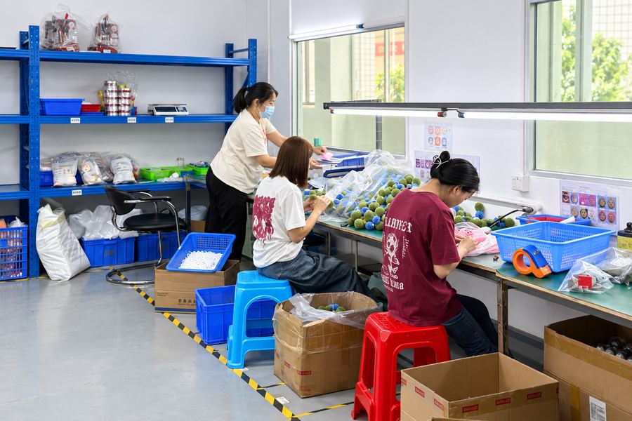 Factory personnel assembling and finishing products at illuminated workstations