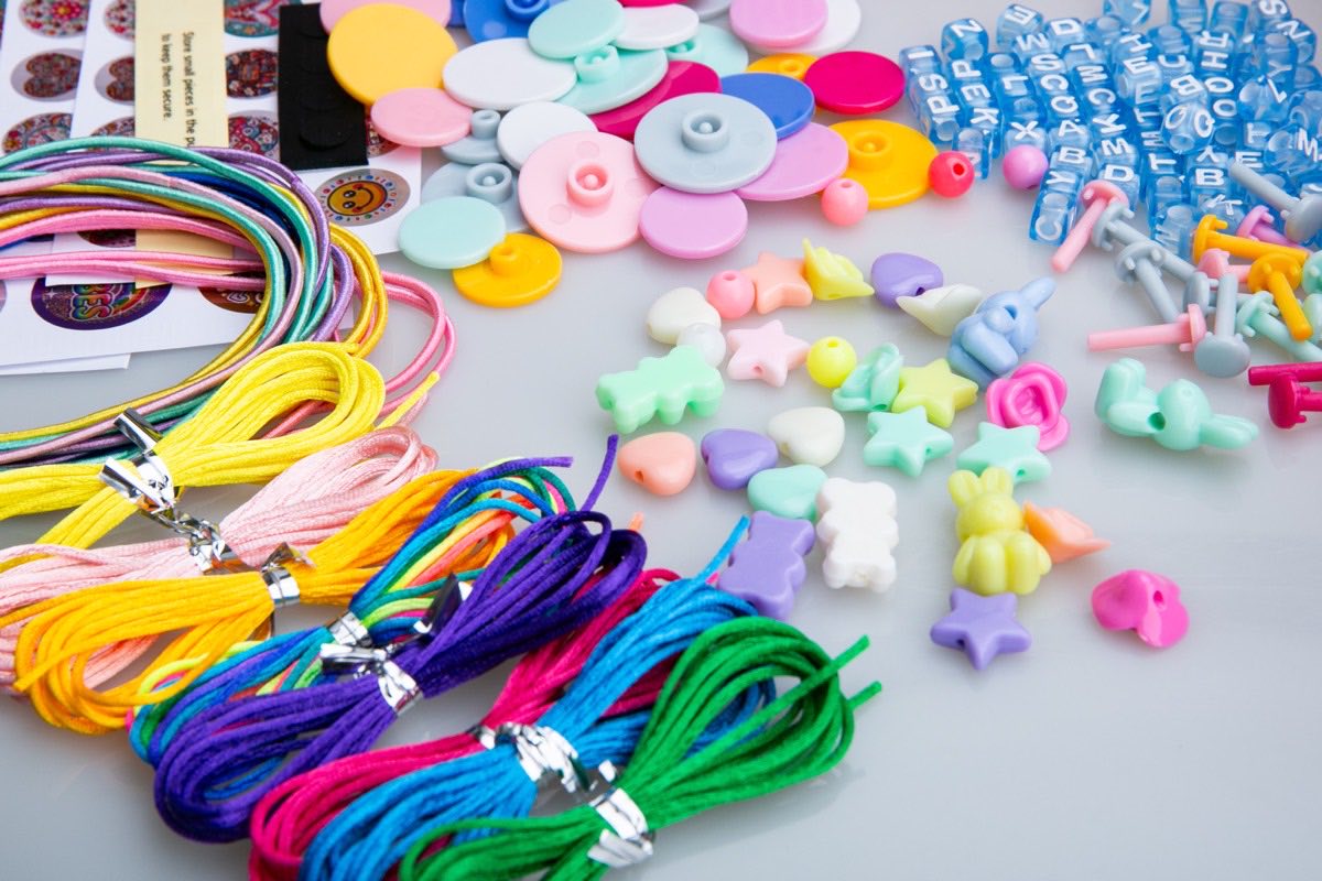 Bracelet-making kit contents: cords, clasps, letter beads, charms, pegs and sticker sheets